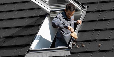 cleaning away leaves on and around a VELUX window