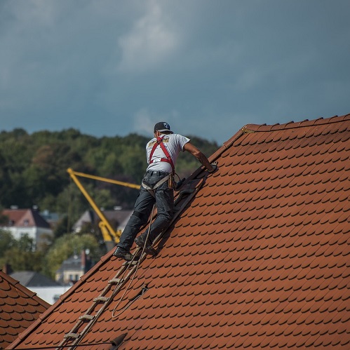 man standing on a ladder and working on the roof