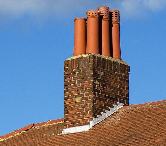 A red brick chimney with lead flashing on the roof.