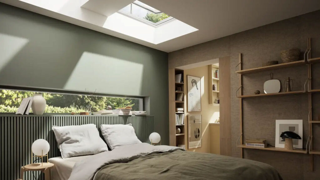 Internal view of VELUX flat roof windows above double bed in modern bedroom with sage green walls and light wood furniture and doors