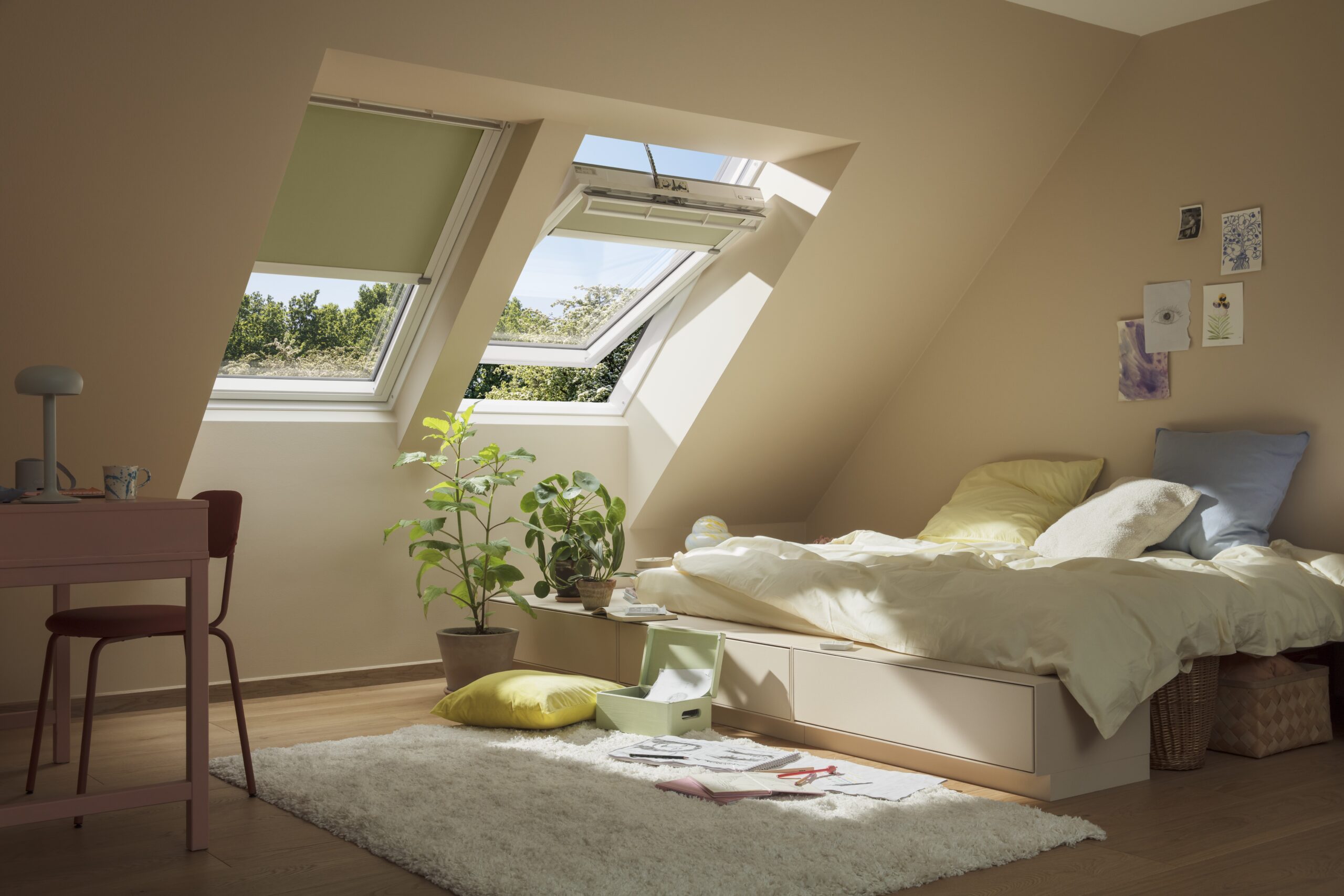 Bright and airy bedroom in loft space with two pitched roof windows. One on the left has the blinds closed, showing how dark they can make the room. The one on the right has the blind up with the window open, showing how bright the room can be.